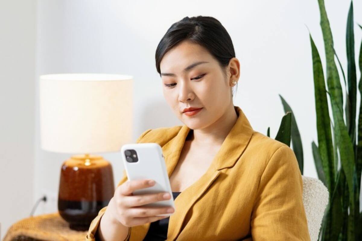 Young professional checking financial updates on a smartphone amid changing trump tariff policies.