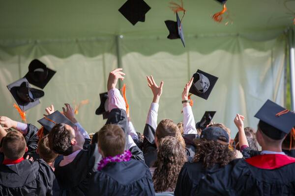 A photo of a group of people wearing graduation gown while tossing their caps