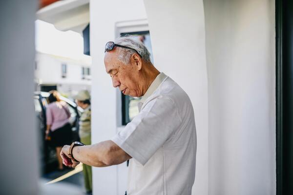 A photo of an old man looking at his wristwatch