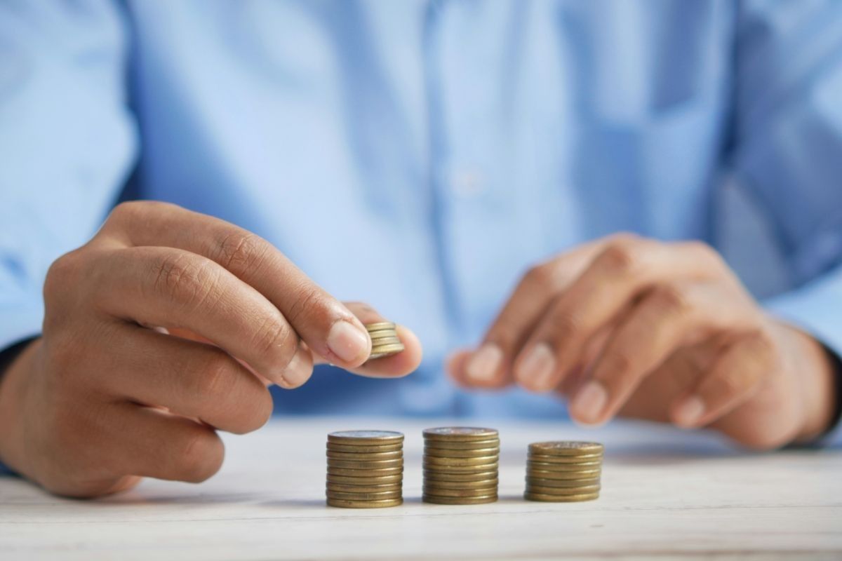 Person stacking coins to grow savings through money market funds.