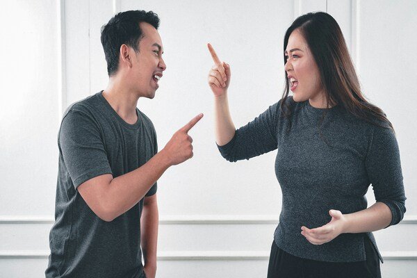 A photo of a couple both in gray coloured tops while arguing with each other