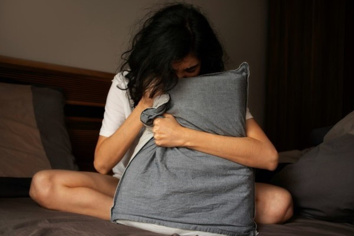 Person hugging a pillow during a restless night, illustrating insomnia and how to improve sleep quality.