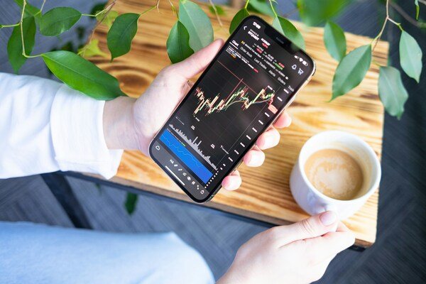 A close-up photo of a smartphone screen displaying an investment graph, held in someone's hand