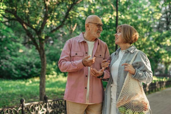 A photo of a senior couple looking at each other while walking together
