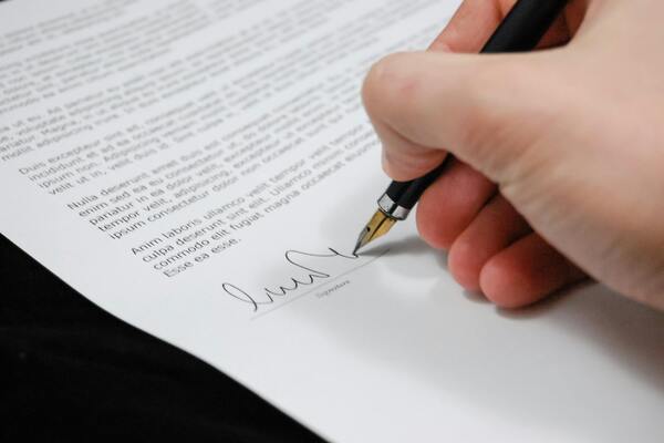 A close-up photo of a person signing a document