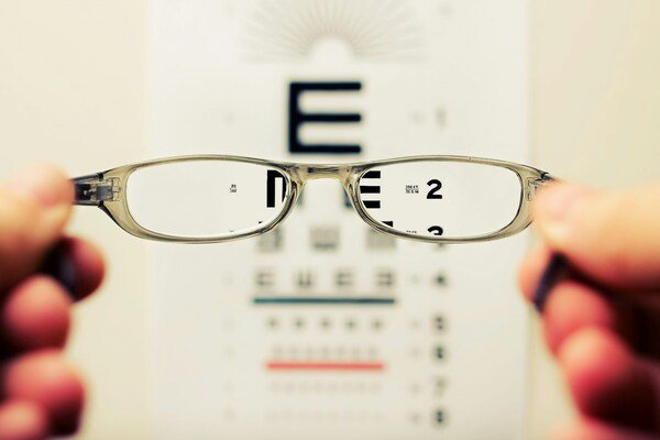 A photo of an eyeglass being held by a person's hands