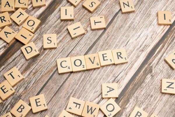 A photo of wooden text blocks arranged on a table to form the word cover
