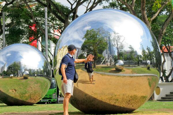 A photo of a man looking at his reflection in a big crystal ball