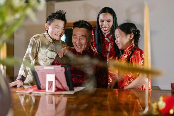A photo of an asian family happily looking on a gadget