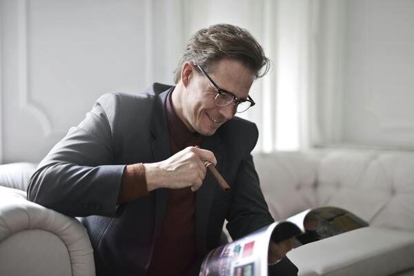 A photo of a man wearing eye glasses while reading a magazine