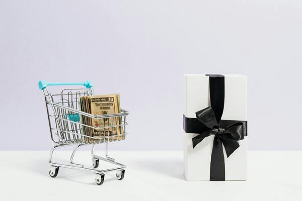 A photo of a small shopping cart beside a small present