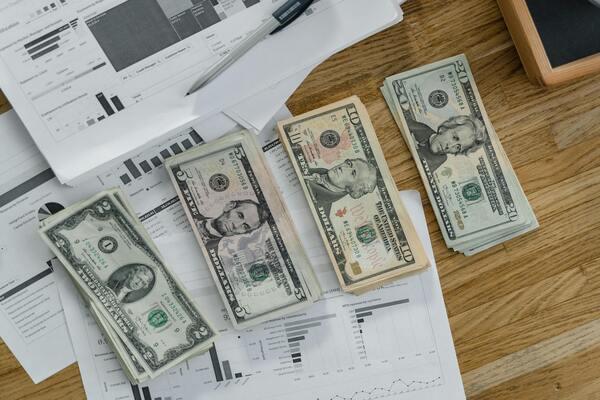 A photo of paper bills placed on the table beside some papers