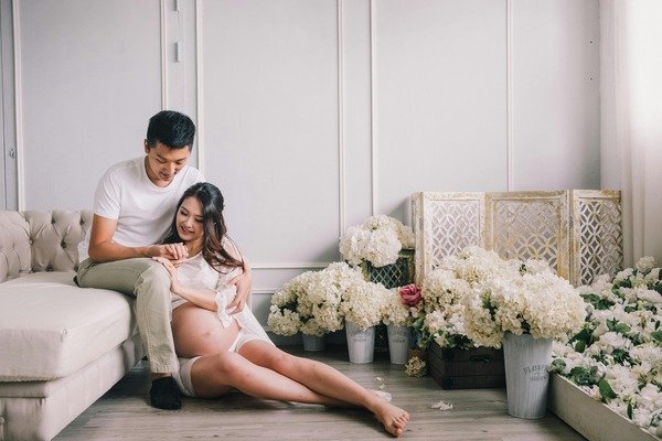 A photo of a couple in the living room taking maternity shoot