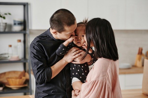 A photo of a couple both kissing a baby in the face
