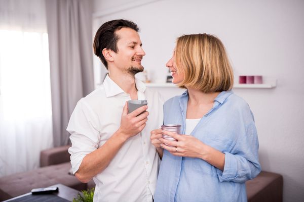 Couple sharing coffee at home while discussing splitting bills 50/50 with partner.
