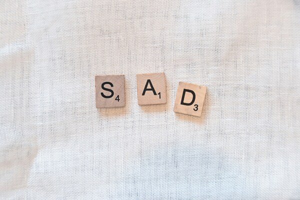 A photo of 3 wooden letter blocks displaying the word sad