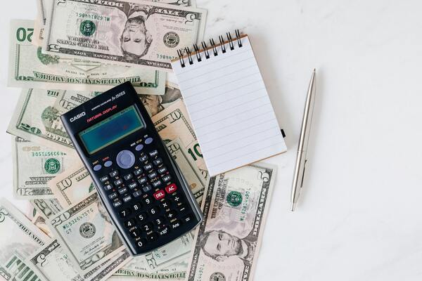 A photo of a paper and a calculator stacked on paper bills