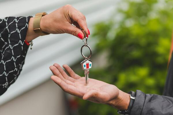 A photo of one hand handing a house key to another hand