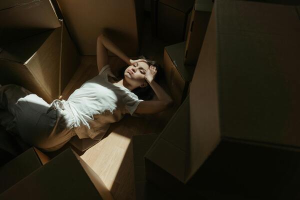 A photo of a woman lying on a brown cardboard box