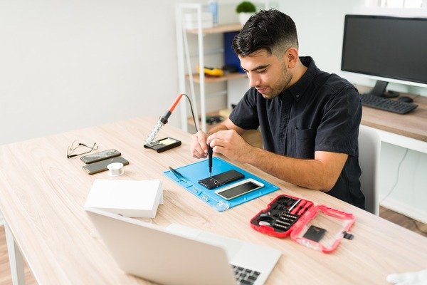 A male technician doing cellphone repairs