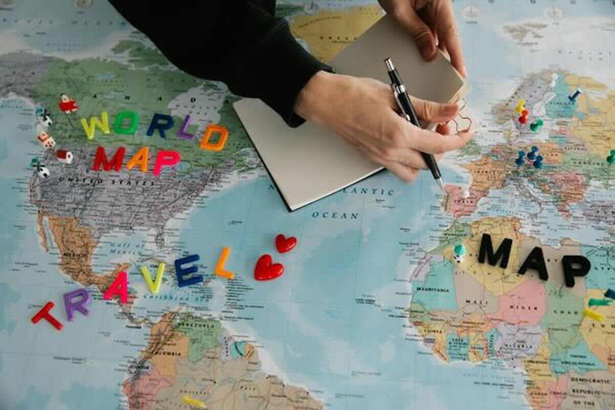 Travel planning with a world map and notebook, illustrating how geoarbitrage can reduce living costs.