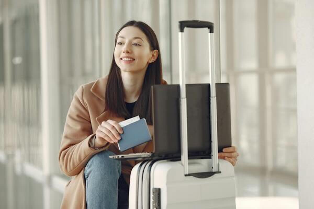 Traveller with a suitcase, passport and laptop preparing for a geoarbitrage move abroad.