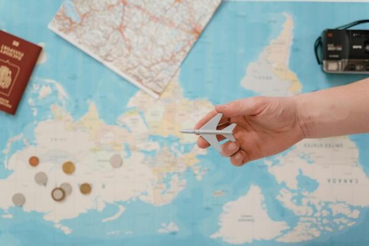 Hand holding a model aeroplane over a map while planning a geoarbitrage destination.
