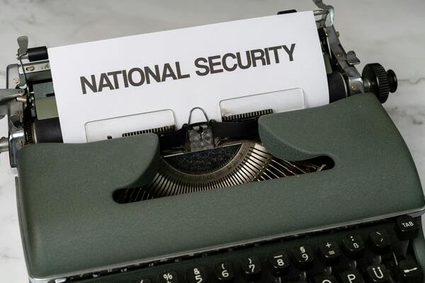 Close-up of a typewriter holding a sheet of paper with the words “national security” typed on it.