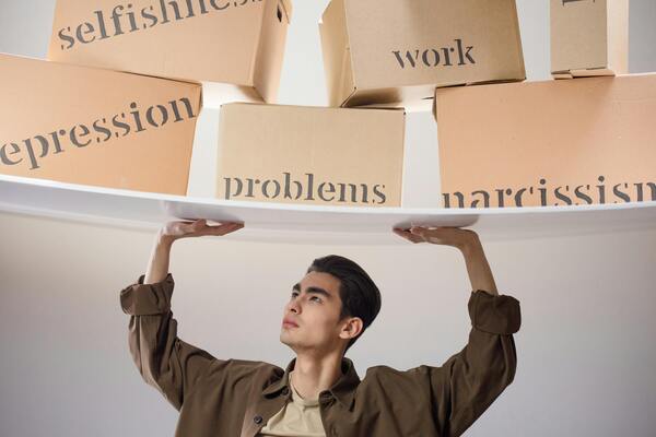 A photo of a man standing with arms raised, holding boxes labelled with problems