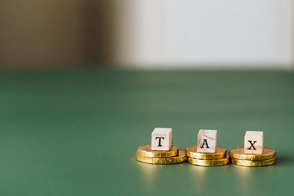 A photo of wooden text blocks spelling out the word tax placed above the coins