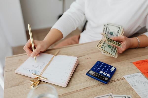 A photo of a person counting paper bills and using a calculator