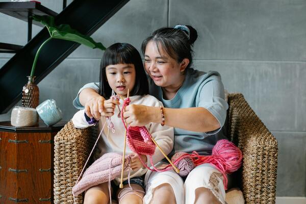 A photo of a young girl and an old woman learning how to knit