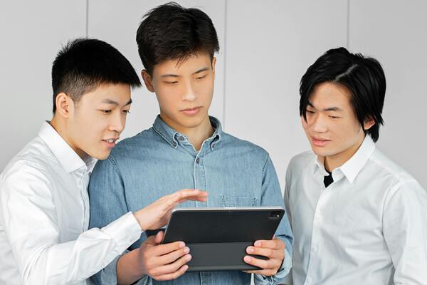 A photo of a group of men looking together at a tablet