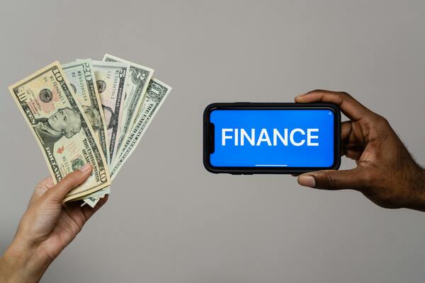 A photo of paper bills and a mobile phone with the word finance on screen