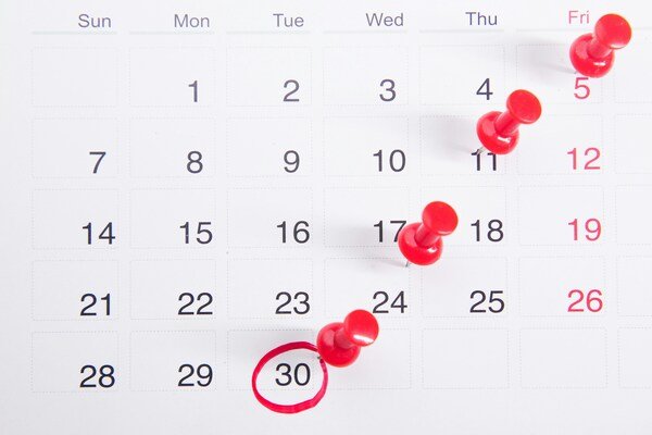 A calendar with red push buttons pinned to it