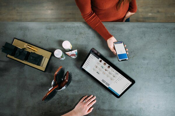 A person holding a smartphone next to a tablet computer on a table