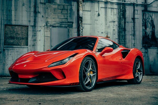 A red Ferrari 458 Italia parked in front of a gray building.