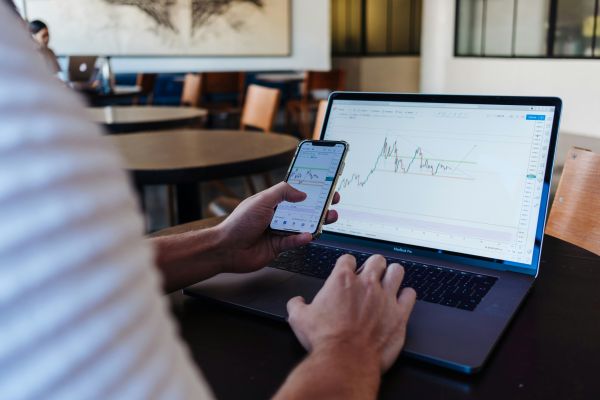 Investor analysing stock charts on a laptop and smartphone before choosing to invest in Singapore Depository Receipts.