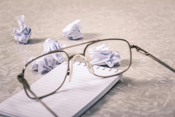 Close-up photography of an eyeglass near crumpled papers