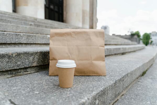 Brown paper bag lies alone on a textured gray concrete floor