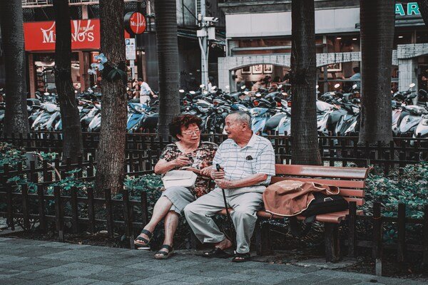 Man and woman sitting on a wooden bench during daytime.