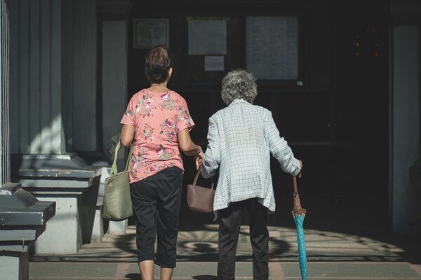 Man in a white and blue checked shirt standing beside a woman in a pink shirt.