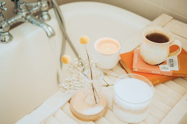 Cup of coffee and books on the edge of a bathtub.