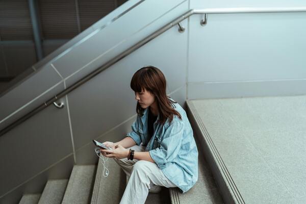 Asian woman using social media on her smartphone while sitting on stairs