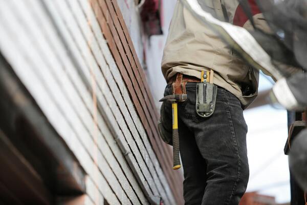 Man wearing black denim pants carrying a hammer in a holster