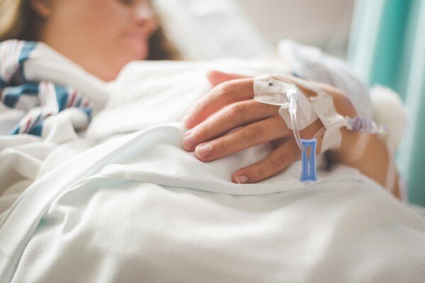 Woman laying in a hospital bed with an IV in her hand