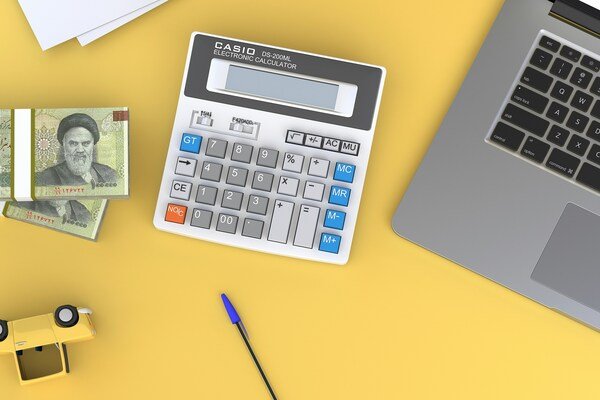 Calculator sitting on top of a desk near a laptop