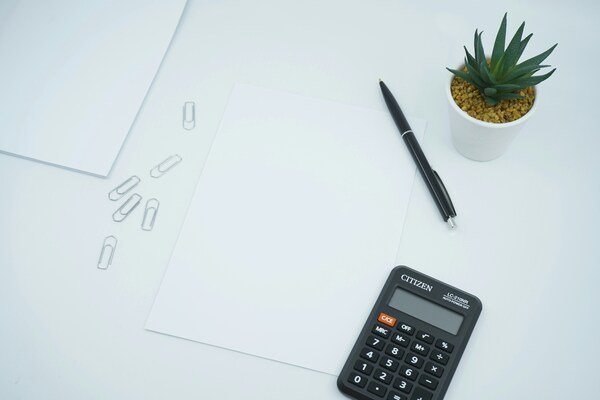 Black calculator beside black pen on white paper
