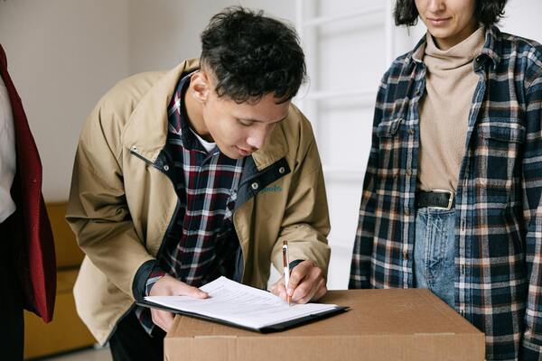 A man in a brown jacket signing papers