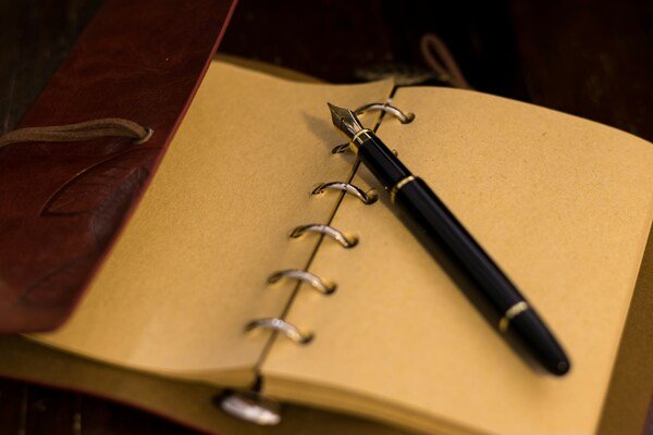 Opened notebook on a table with a pen placed on it
